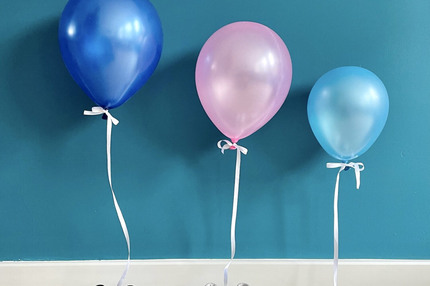 due paia di scarpe di adulto e un paio di scarpe da bebè con attaccati dei palloncini