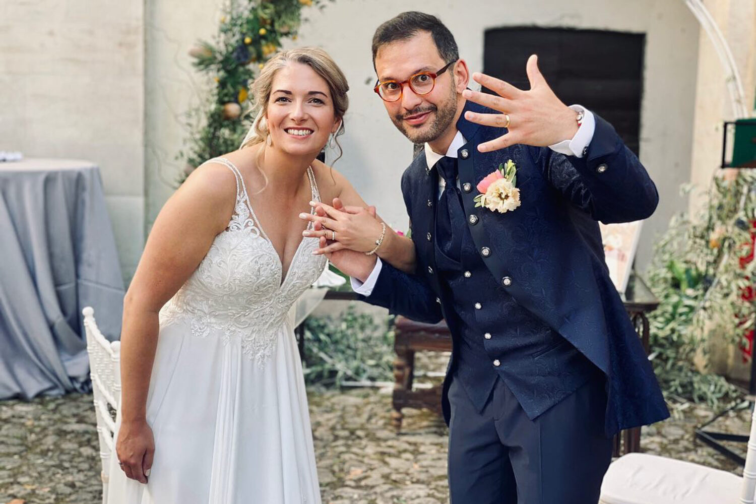 marito e moglie in abito da sposi fanno vedere gli anelli