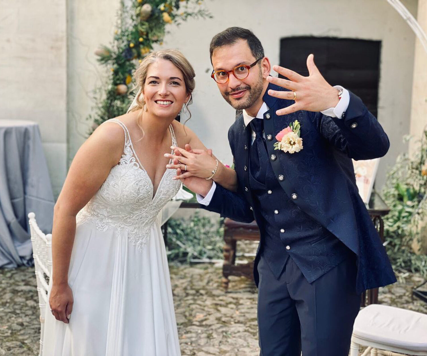 marito e moglie in abito da sposi fanno vedere gli anelli