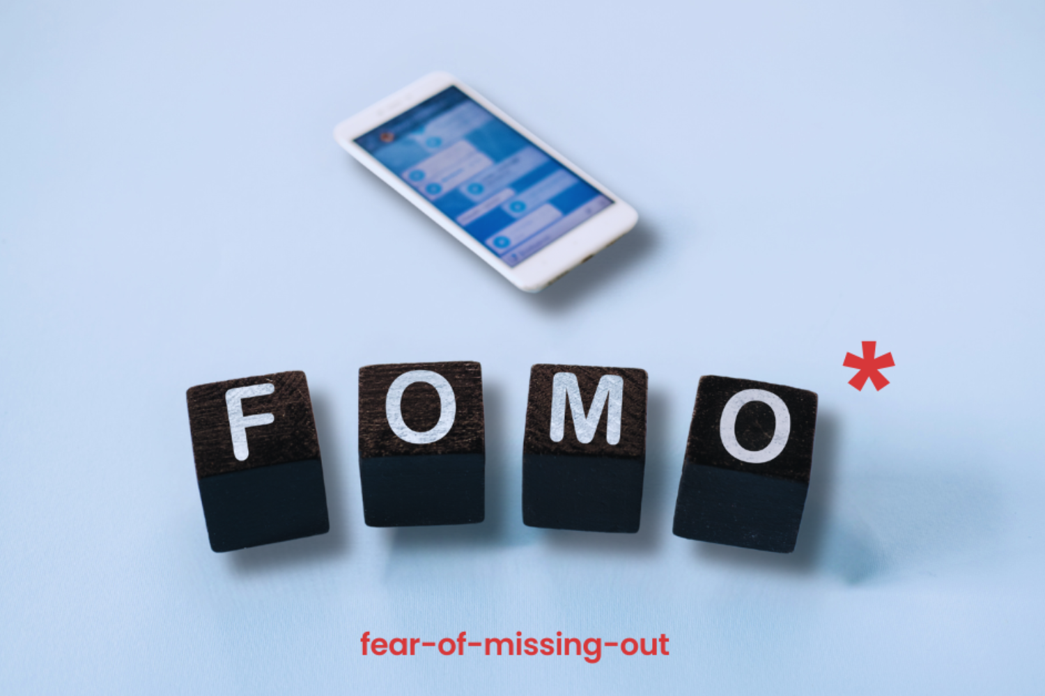 tessere domino che formano la parola FOMO. Sullo sfondo un cellulare.