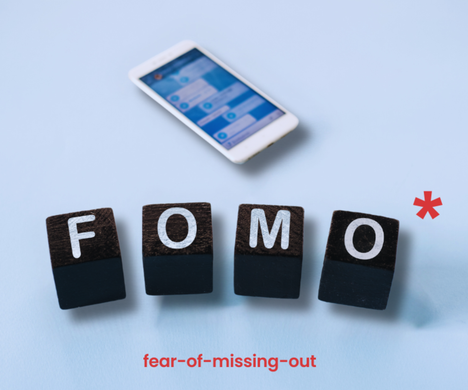 tessere domino che formano la parola FOMO. Sullo sfondo un cellulare.